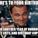 Leonardo DiCaprio giving a sarcastic toast with a paper cup in an office birthday setting.